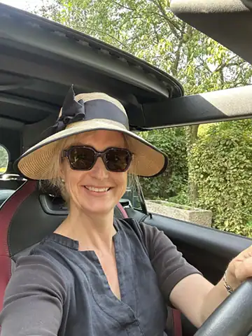 Elske behind the wheel of a convertible wearing a sun hat and sunglasses, symbolising the freedom and joy of slow travel across France.